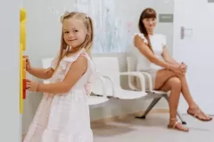 Uśmiechnięta dziewczynka wraz z mamą w poczekalni przychodni